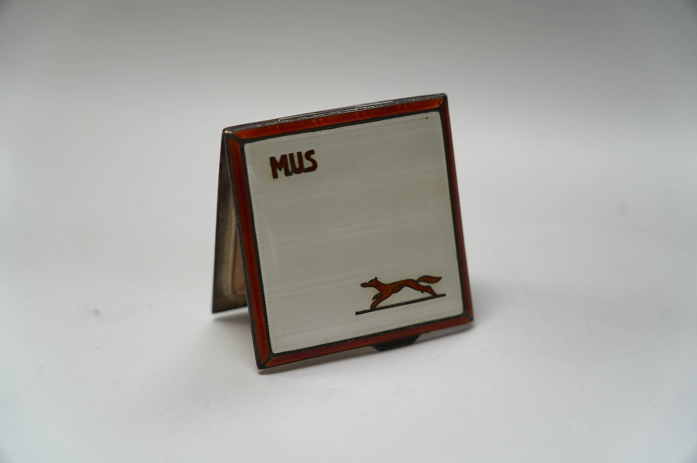 A George V silver and enamel compact, with initial and decorated with a fox, Adie Bros, Birmingham, 1936, 73mm. Condition - fair